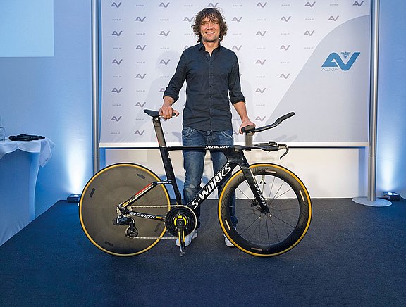 Foto: Ultraradfahrer Christoph Strasser mit Rennrad vor Werbewand der AUVA