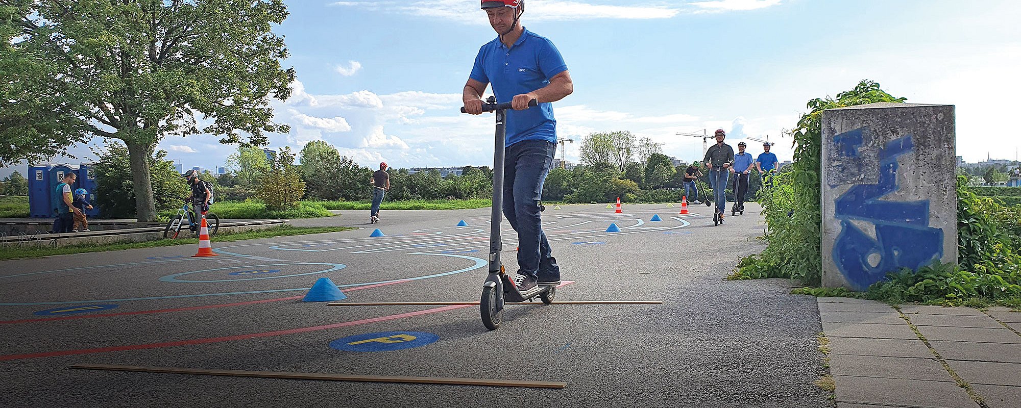 Foto: Erwachsene auf einem asphaltierten Übungsparcours für E-Scooter auf der Donauinsel in Wien
