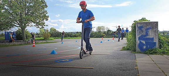 Foto: Erwachsene auf einem asphaltierten Übungsparcours für E-Scooter auf der Donauinsel in Wien